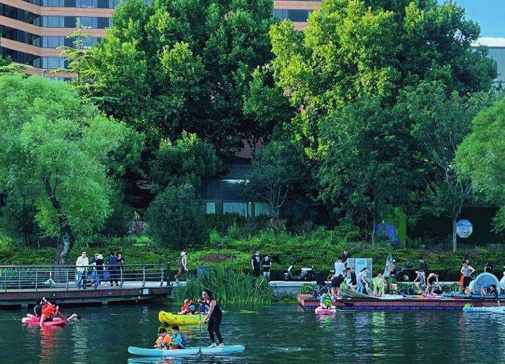 亮马河改造后滨水景观廊道实景，展示建筑、绿地与水体的无缝衔接