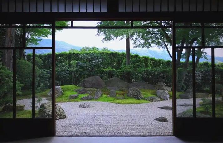 一张典型的枯山水景观设计图，前景是耙制出波纹状纹理的白砂，象征着水面。白砂上有几组精心摆放的天然石块，象征着山峦或岛屿，旁边点缀着青苔，整体风格简约、抽象，充满禅意。